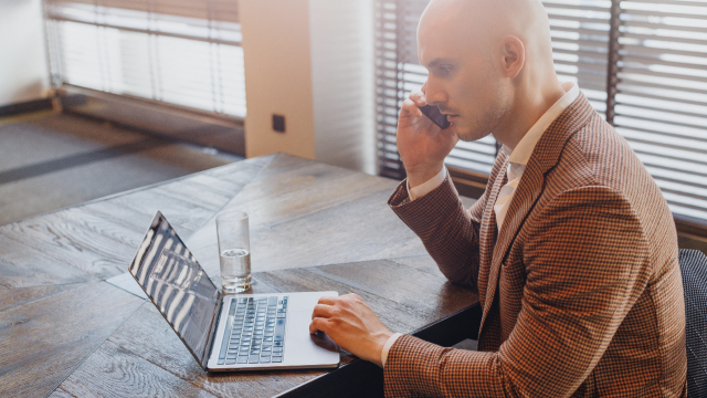 Lead magnet dopasowany do grupy docelowej. Biznesman rozmawia przez telefon jednocześnie obsługując laptopa.