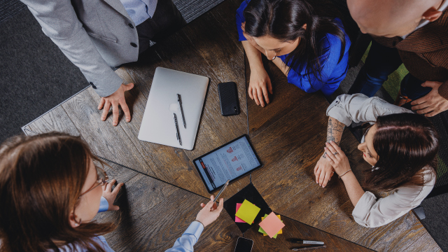 Jak może wyglądać skuteczny lead magnet? Grupa osób siedzi przy stole i omawia lead magnet wyświetlony na tablecie.