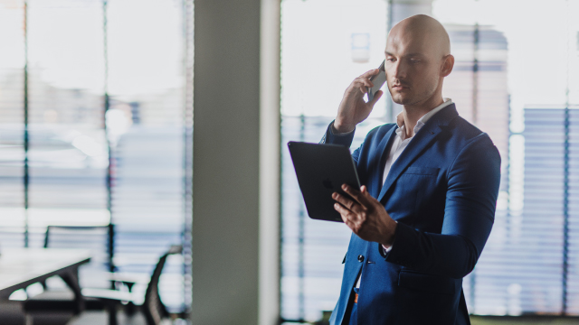 Lead magnet na własnym landing page'u i w mediach społecznościowych. Biznesmen rozmawia przez telefon, jednocześnie patrząc na tablet. 